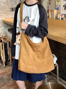 Detail of a large brown hobo bag with wide shoulder strap and cute puppy pendant