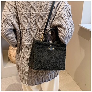 Fashionable black faux shearling tote bag with leather patches worn with grey knitwear
