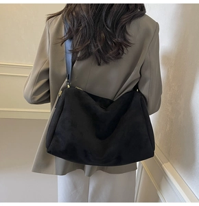 Detail of minimalist black suede hobo bag with gold zipper and matte finish strap