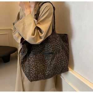 Détail d'un grand cabas en toile à motif léopard porté avec un trench-coat beige