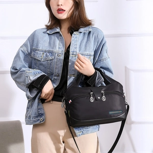 Vue détaillée du sac bandoulière noir en tissu Oxford avec étiquette mode et zips