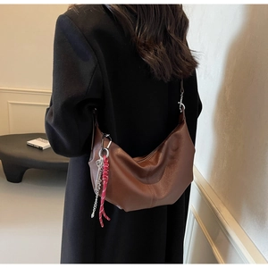 Detail of brown litchi pattern PU leather tote bag with unique metal key charm and soft texture