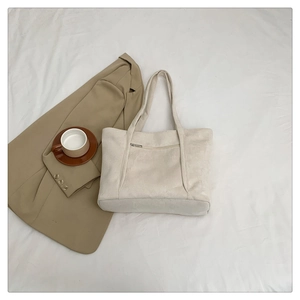 Minimalist off-white suede tote bag with front zipper pocket and long shoulder straps