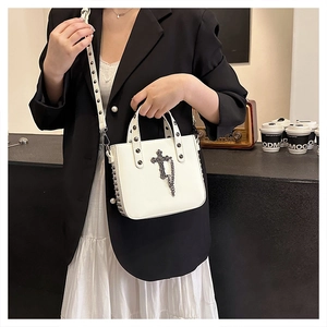 Detail of white PU leather crossbody bag with metal cross charms and rivet strap decoration