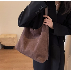 Detailed texture of a brown suede hobo tote bag worn by a model in a minimalist room