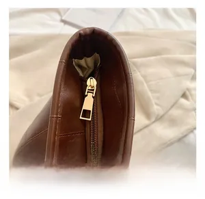 Detailed close-up of premium dark brown leather shoulder bag with gold zipper hardware