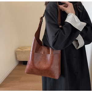 Caramel brown PU leather hobo bag shown with adjustable wide shoulder strap and pocket