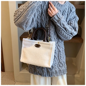Detail of soft white plush fabric tote bag with brown leather handle and metal accents
