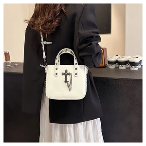 Detail showing Gothic white PU leather handbag with black cross and silver rivets on model