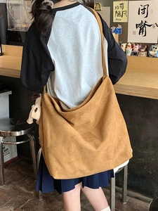 Detail view of caramel suede crossbody bag with wide strap and plush dog keychain