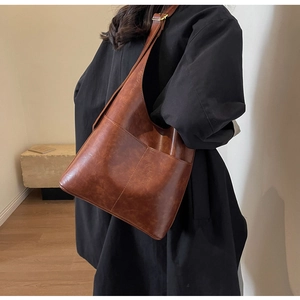 Detail of adjustable shoulder strap and visible stitching on dark brown PU leather tote bag