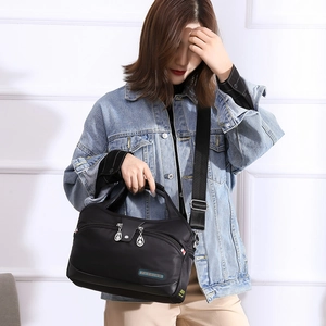 Détail du sac bandoulière noir en nylon imperméable avec fermetures éclair sur tenue