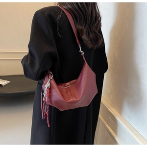 Detail view of the deep burgundy PU leather half-moon crossbody bag with creative charm