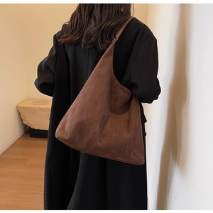Detail view of large dark coffee suede tote bag styled on a person's shoulder