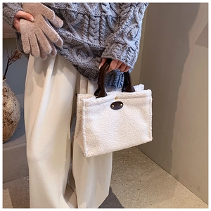 Detail of white plush tote bag with brown leather handles and center patch accents