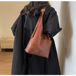 Close-up of vintage brown PU leather shoulder bag with side pocket and golden buckle