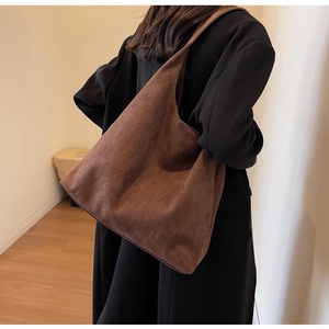 Side view of large brown suede tote bag showing natural drape on a model during daily commute