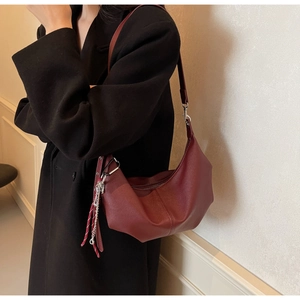 Fashionable burgundy crescent PU leather crossbody bag worn over a black wool winter coat
