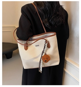 Detail view of retro canvas tote bag with brown leather trim and cute teddy bear pendant