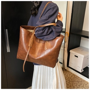 Detail view of large brown vintage tote bag with quilted texture shown on shoulder