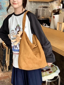 Detail of warm brown suede hobo bag featuring a cute dog plush charm in a cafe setting