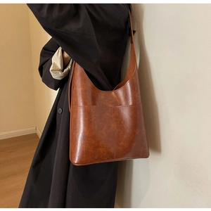Close-up of brown PU leather tote bag with large front pockets and fine texture detail