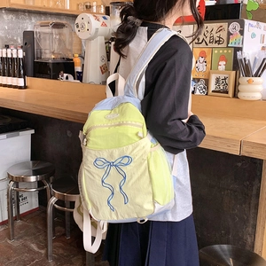 Detail eines Nylon-Rucksacks mit Schleifenstickerei und blauen Akzenten im Café-Szenario