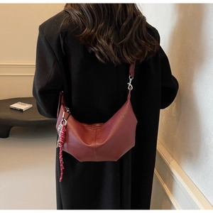 Detail of burgundy PU leather hobo bag with textured finish and woven cord charm