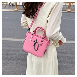 Close-up of pink PU leather crossbody bag with gothic cross and silver rivet straps