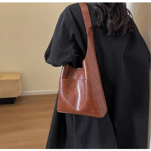 Detailed view of brown PU leather shoulder bag with fine stitching on a model