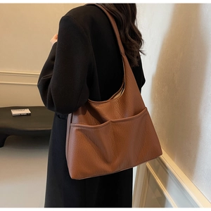 Detail of a brown lychee-textured PU leather tote bag with functional front pockets