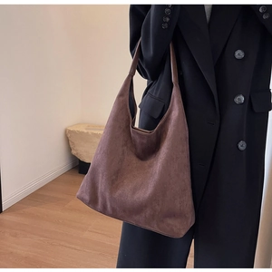 Brown suede hobo bag shown over a black coat for a casual and stylish commute look