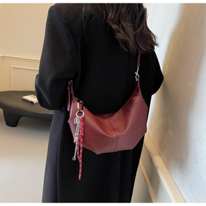 Macro detail of wine red PU leather underarm bag with decorative woven rope and metal chain