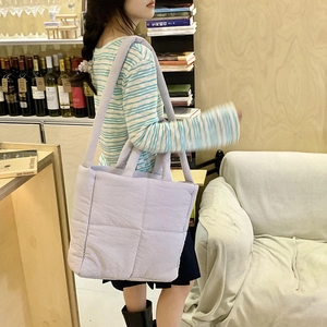 Dettaglio di una borsa tote trapuntata in velluto a coste lilla chiaro su una modella