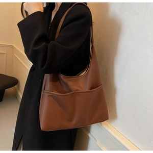 Brown PU leather tote bag with lychee texture and two front pockets shown on a model