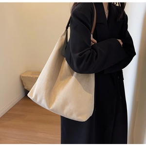 Detailed view of beige suede hobo tote bag with brown leather strap on model
