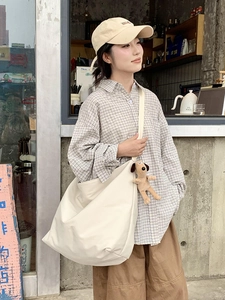 Close-up of beige crossbody tote bag featuring a cute brown puppy plush keychain charm