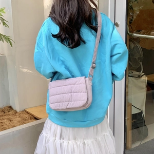 Outdoor shot of a lilac quilted crossbody bag with adjustable strap and puffy texture