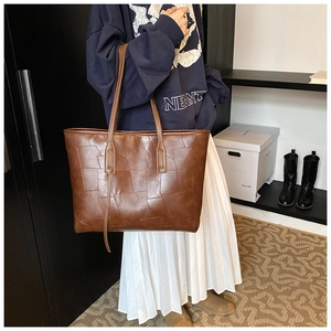 Detailed view of brown PU leather tote bag with geometric stitching and dual straps