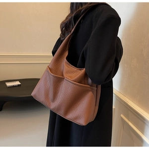Detail of caramel faux leather shoulder bag with lychee texture and two front pockets