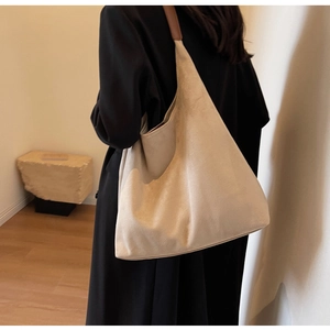 Detail of a large suede tote bag with brown leather straps worn over the shoulder