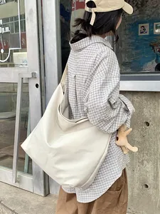 Model wearing a creamy white large capacity tote bag with a cute rabbit plush pendant