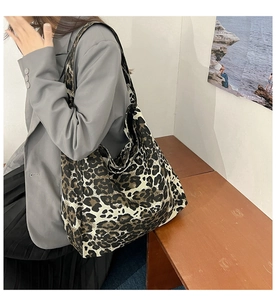 Sac fourre-tout en toile léopard porté avec un blazer gris et une jupe plissée noire