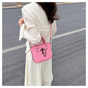 Pink gothic cross crossbody bag with stud detail and chain shown on street model