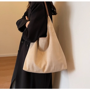 Close-up of beige suede tote bag featuring contrasting brown shoulder straps on a model