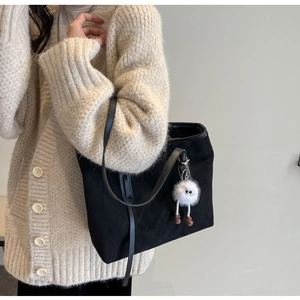 Detail of black velvet tote bag with white plush charm worn with autumn knit cardigan