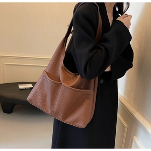 Detailed macro view of the brown textured faux leather shoulder bag with large front pockets