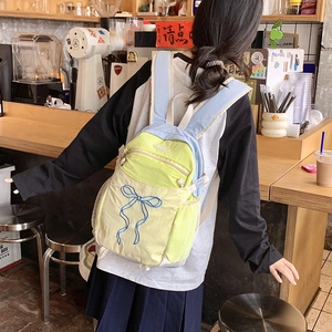 Detail eines gelb-blauen Nylon-Rucksacks mit Schleifenstickerei und seitlicher Netztasche