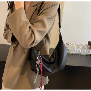 Detail of a black PU leather hobo bag featuring a unique silver key and rope charm pendant