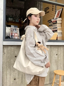 Chic beige tote bag with a cute plush dog pendant shown in a casual outdoor cafe setting
